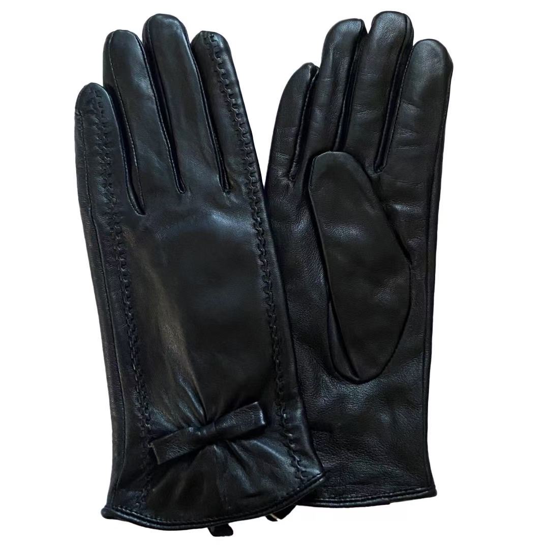 Svarta damhandskar i lammskinn med dekorativa linjer och rosett.